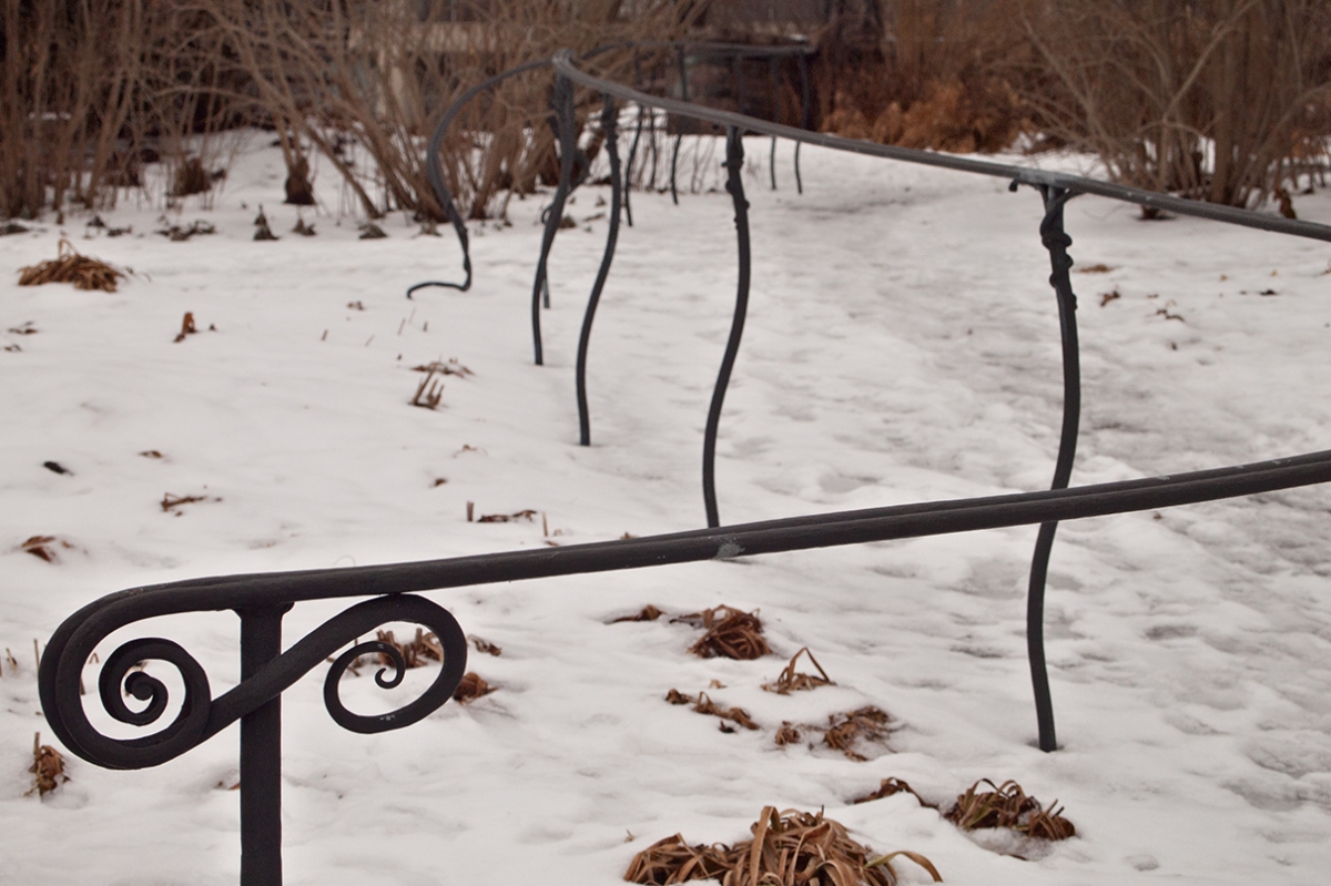 Handrail beside snowy path.