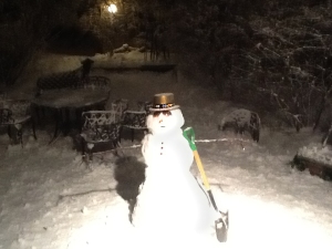 A snowman in New Year's Eve hat in a backyard.